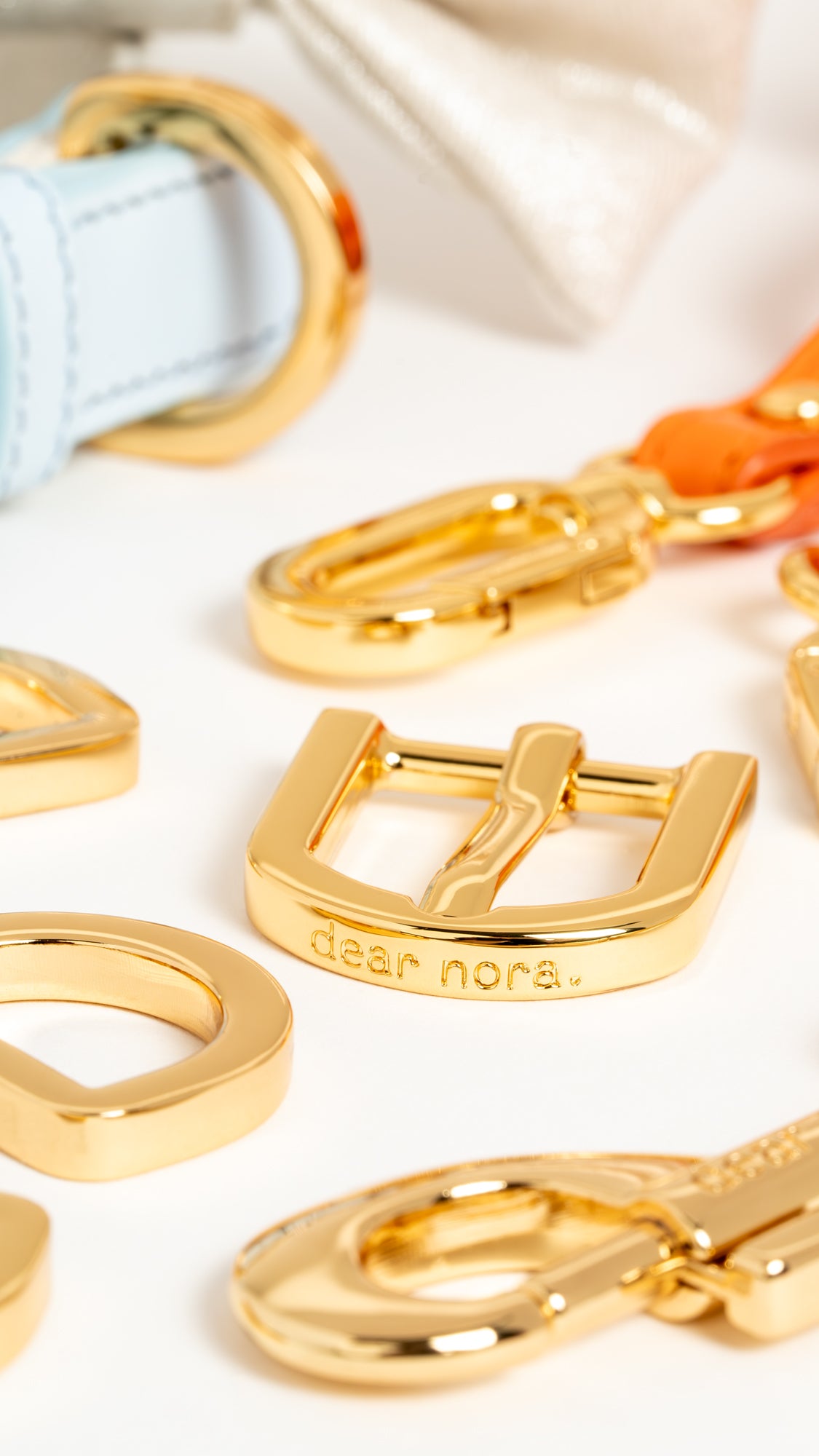 Macro shot close up of 24k gold plated metal hardware with Dear Nora engraved on the buckle and dog hook